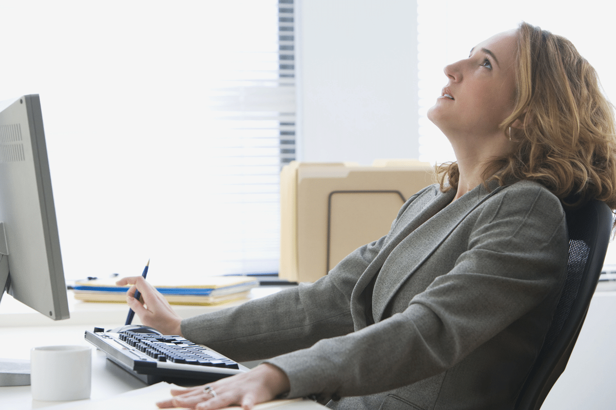 business woman sitting at desk lookingn up at ceiling